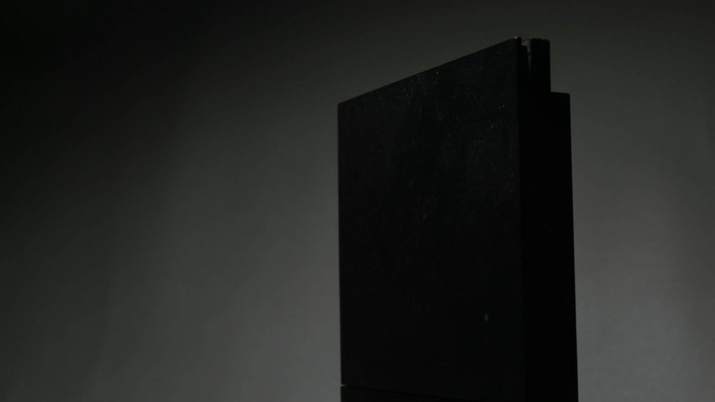 Dark rectangular object standing upright on a grey background.