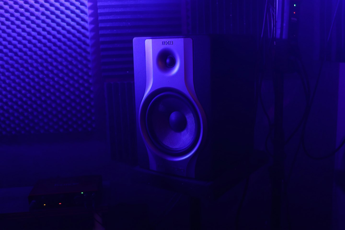 Studio monitor speaker mounted on a wall with acoustic foam.