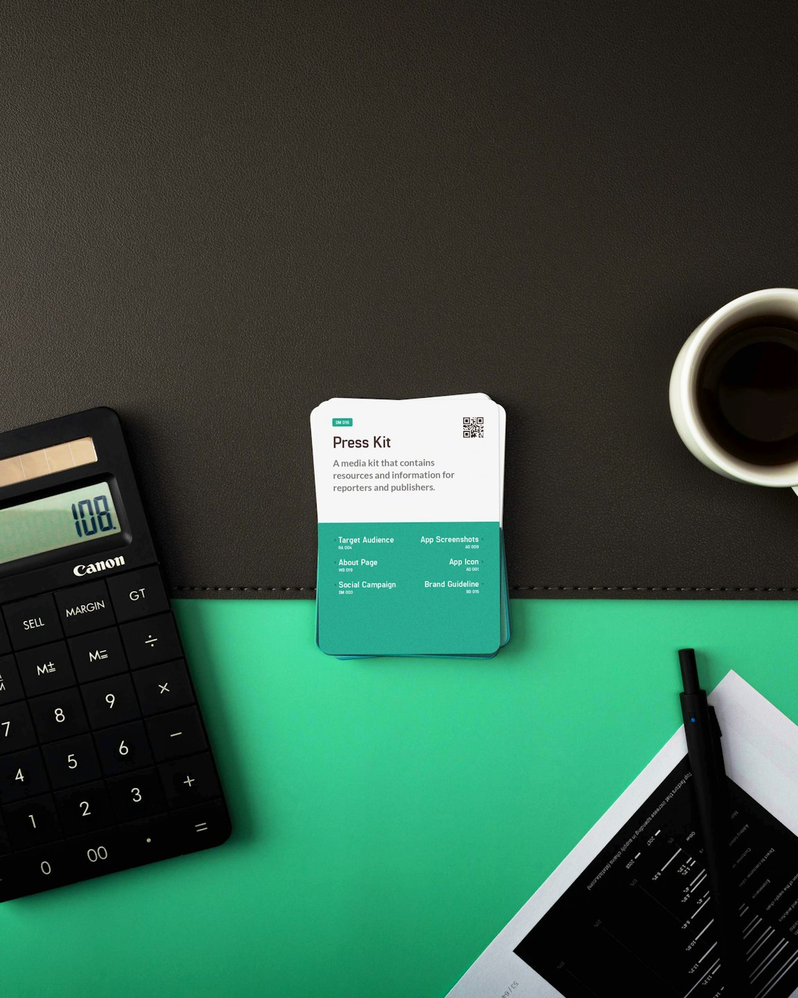 Desk with calculator, press kit cards, and coffee cup.