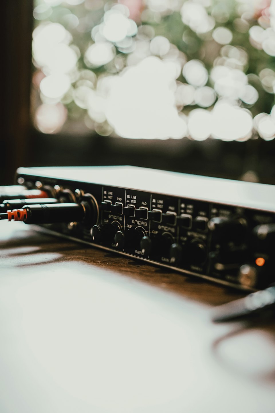 Audio interface with connected cables resting on a wooden desk.